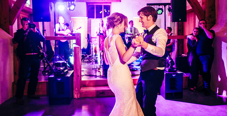 Couples first dance in cider barn in front of band