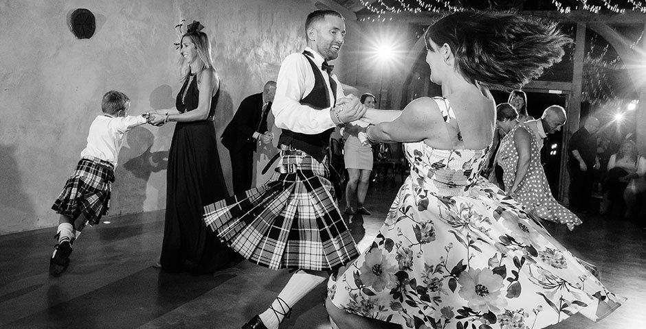 Kilted groom dances with guest